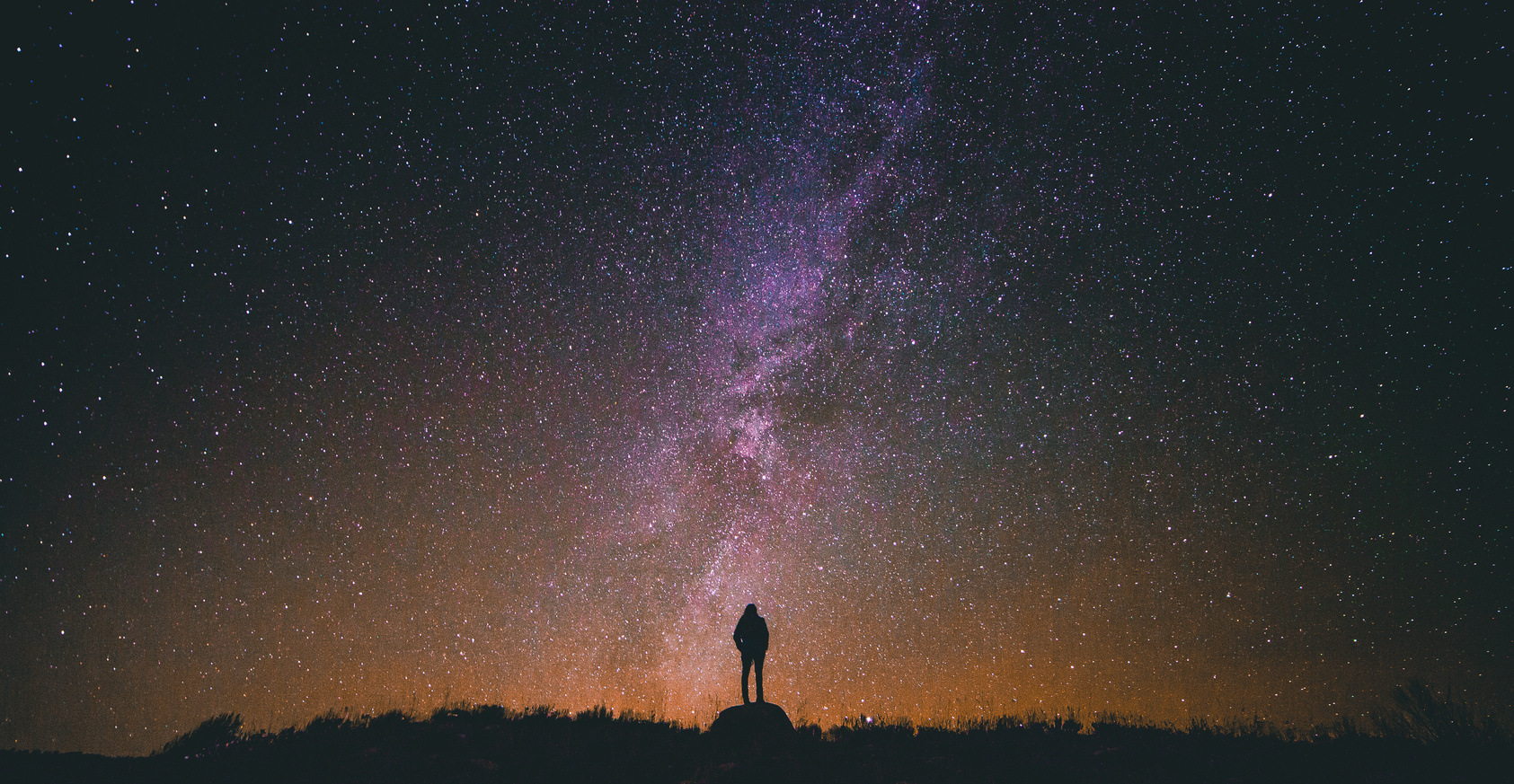 Silhouette Photo of a Person Standing on Rock